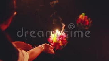 在泰国庆祝LoyKratong节。 双手捧起池塘里的鲜花和蜡烛